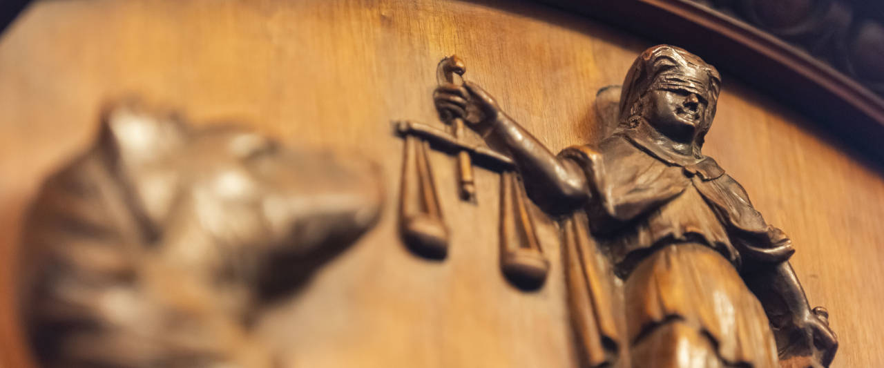 A woodcut of the Law Society crest with lady justice and a wolfhound
