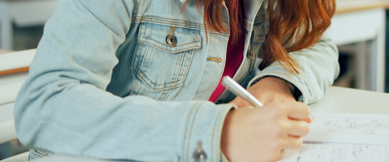 A student completing an exam with notebook and pen