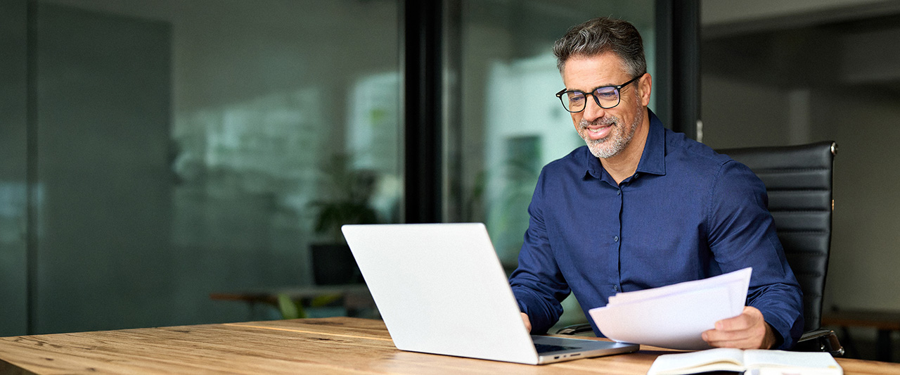 A  maleprofessional in their office managing paper and digital records