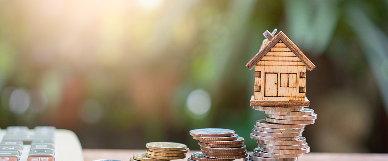 A model house balanced on a pile of coins